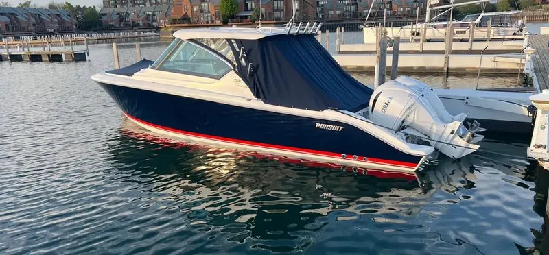  Yacht Photos Pics 2022 Pursuit DC 295 Dual Console boat docked in a marina, featuring sleek design and twin engines.