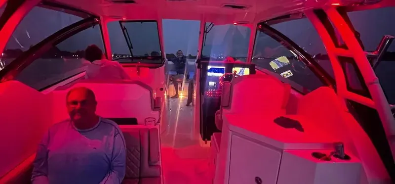  Yacht Photos Pics 2022 Pursuit DC 295 Dual Console boat interior with red lighting at night.