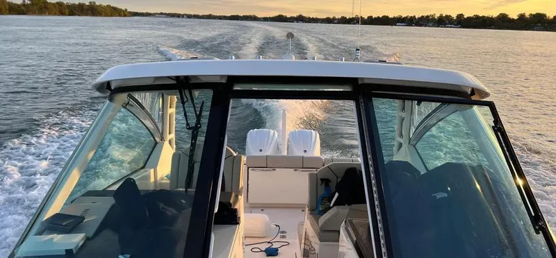  Yacht Photos Pics 2022 Pursuit DC 295 Dual Console cruising on a serene lake at sunset.