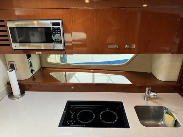  Yacht Photos Pics 2010 Sea Ray 370 Sundancer kitchen with microwave, stovetop, sink, and wooden cabinetry.