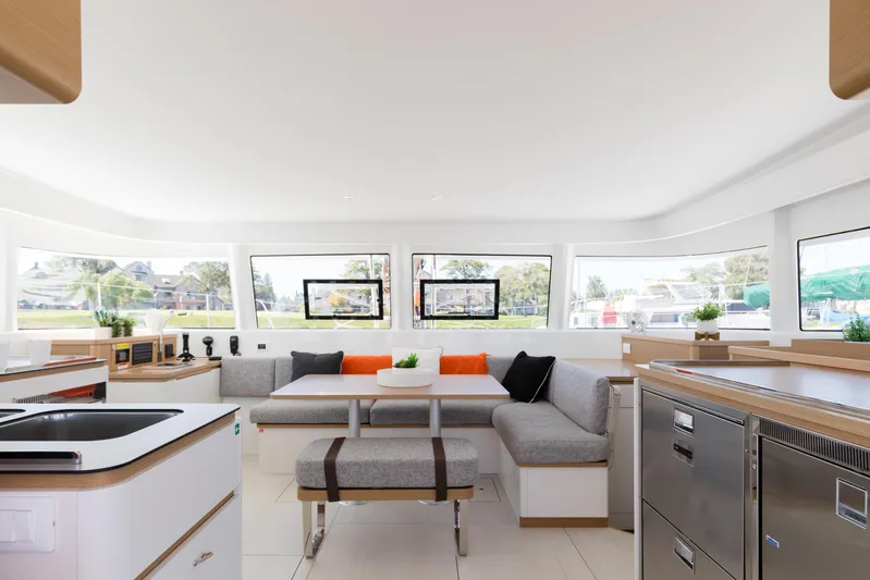 In Stock Yacht Photos Pics Luxurious interior of 2024 Excess 14 catamaran with modern kitchen and seating area.