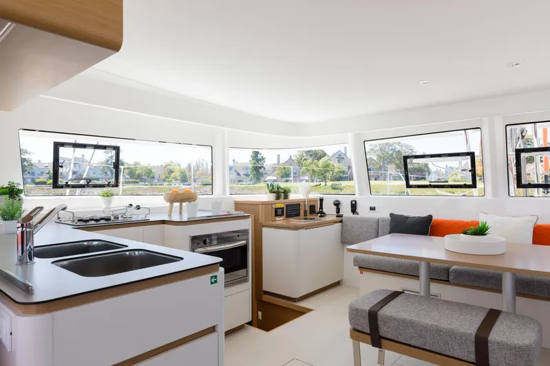 In Stock Yacht Photos Pics Modern interior of 2024 Excess 14 catamaran with kitchen and dining area.