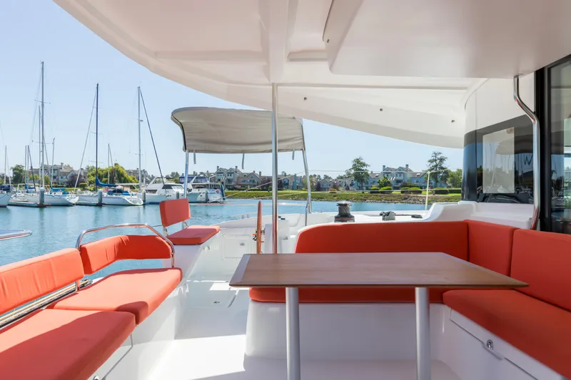 In Stock Yacht Photos Pics 2024 Excess 14 catamaran with red seating, docked in a marina.