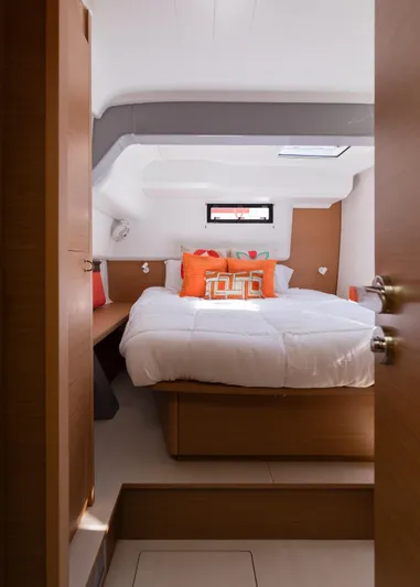In Stock Yacht Photos Pics 2024 Excess 14 yacht cabin with cozy bed and vibrant orange pillows.