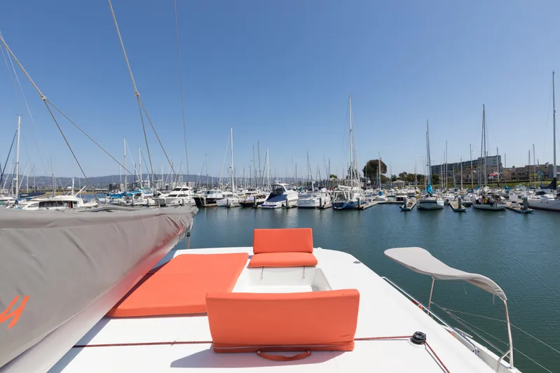 In Stock Yacht Photos Pics 2024 Excess 14 catamaran with orange seating, docked in a marina under clear blue skies.