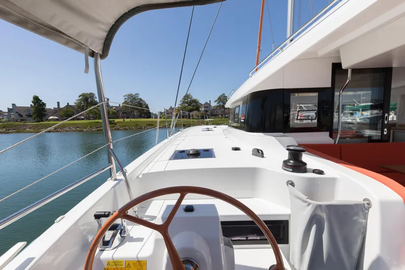 In Stock Yacht Photos Pics Excess 14 yacht deck, 2024 model, with steering wheel and waterfront view.