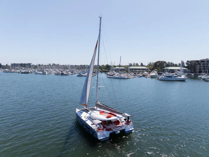 In Stock Yacht Photos Pics 2024 Excess 14 catamaran sailing in a marina with other boats.