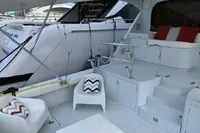 2004 Hatteras 70 Enclosed Bridge yacht with white seating and red cushions on deck.