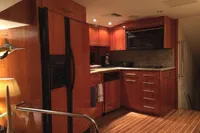 Luxurious kitchen interior of 2004 Hatteras 70 Enclosed Bridge yacht with wooden cabinetry.