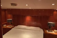 Luxurious bedroom interior of 2004 Hatteras 70 Enclosed Bridge yacht with wood paneling.