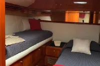 2004 Hatteras 70 Enclosed Bridge cabin with twin beds, wood finish, and red accents.