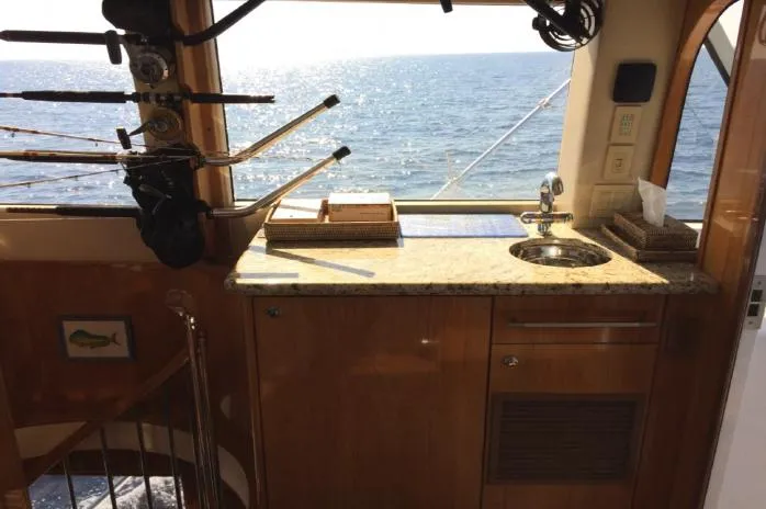  Yacht Photos Pics Interior of 2004 Hatteras 70 Enclosed Bridge yacht with ocean view and fishing rods.