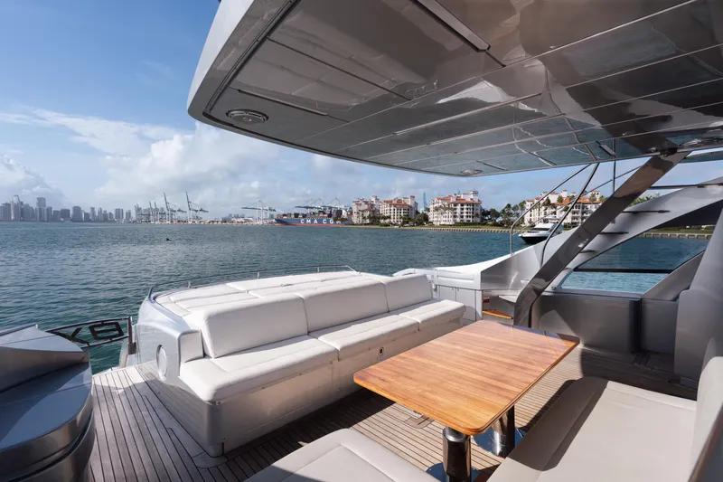 Alexandra Yacht Photos Pics Luxury Pershing 8X yacht deck with seating, ocean view, and city skyline in the background.
