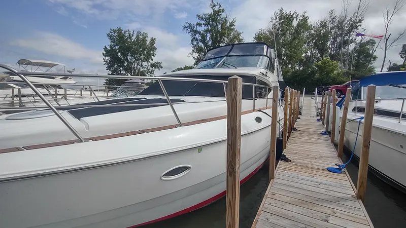  Yacht Photos Pics 2001 Cruisers Yachts 4450 Express Motoryacht docked at marina, surrounded by trees and boats.