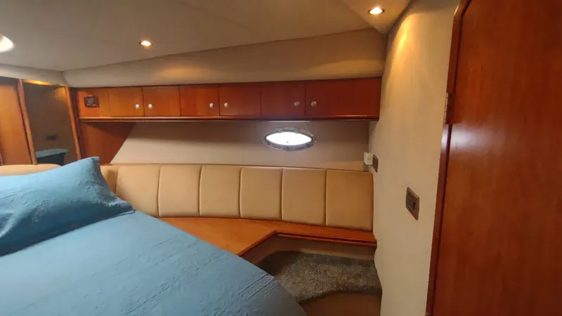  Yacht Photos Pics 2001 Cruisers Yachts 4450 Express Motoryacht interior cabin with wood paneling and blue bedding.