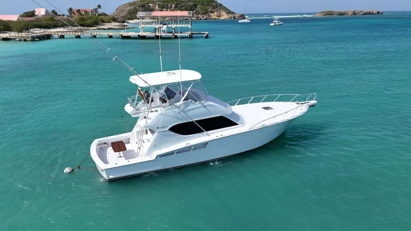  Yacht Photos Pics 2005 Hatteras 50 Convertible yacht on turquoise water near a dock.