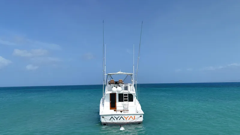  Yacht Photos Pics 2005 Hatteras 50 Convertible yacht anchored in clear blue ocean waters.