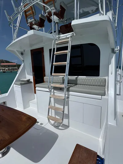  Yacht Photos Pics 2005 Hatteras 50 Convertible yacht with ladder, cushioned seating, and wooden table on deck.