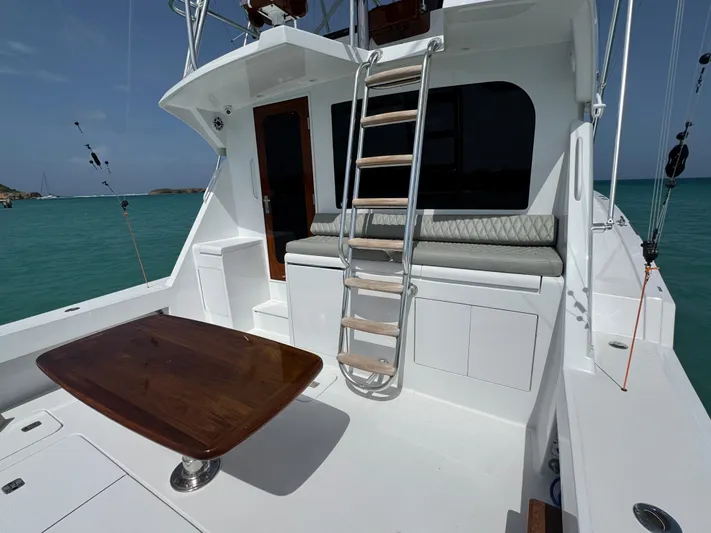  Yacht Photos Pics Hatteras 50 Convertible 2005 yacht deck with ladder, seating, and wooden table.