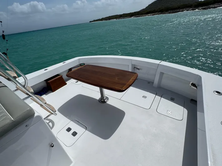  Yacht Photos Pics Hatteras 50 Convertible 2005 yacht deck with table, overlooking turquoise sea and distant shoreline.