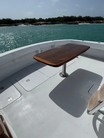  Yacht Photos Pics 2005 Hatteras 50 Convertible yacht deck with wooden table, overlooking turquoise waters.