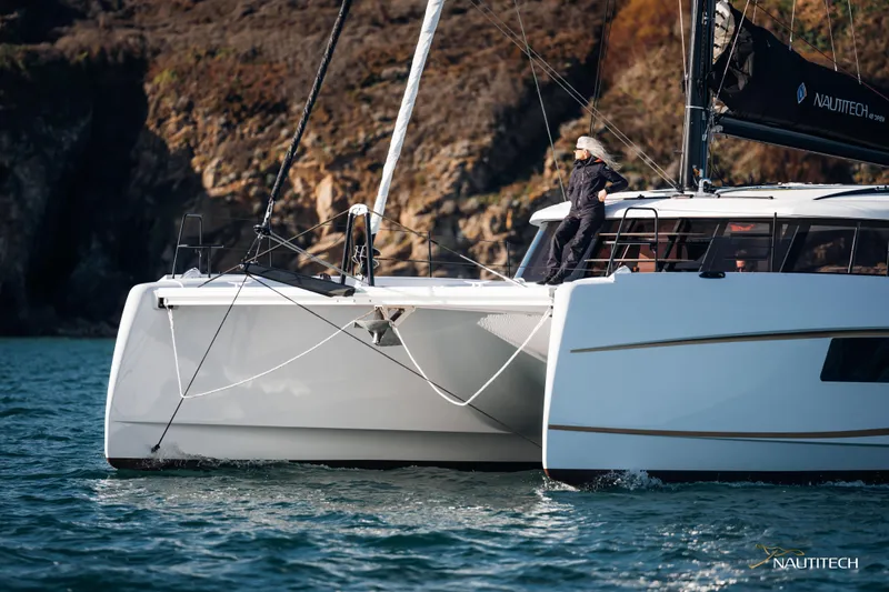 Nautitech 48 Open - Available For 2026 Delivery! Yacht Photos Pics Sleek Nautitech 48 Open catamaran sailing near rocky coastline, 2026 model.