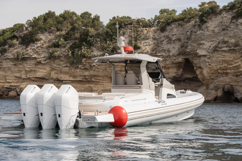 Yacht Photos Pics 2026 SACS NEW Strider 13 boat with four engines, anchored near rocky cliffs.