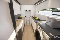 Modern laundry area in Nautitech 48 Open yacht, featuring washer, storage, and scenic window view.