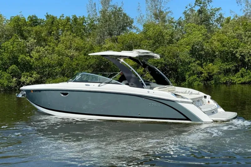  Yacht Photos Pics 2020 Cobalt R30 boat cruising on a calm river, surrounded by lush greenery.