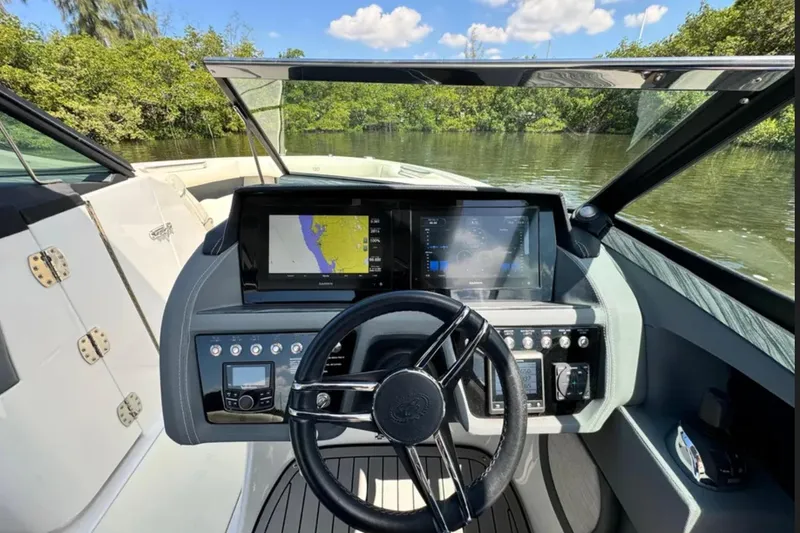  Yacht Photos Pics 2020 Cobalt R30 boat dashboard with navigation screens and steering wheel on a sunny day.