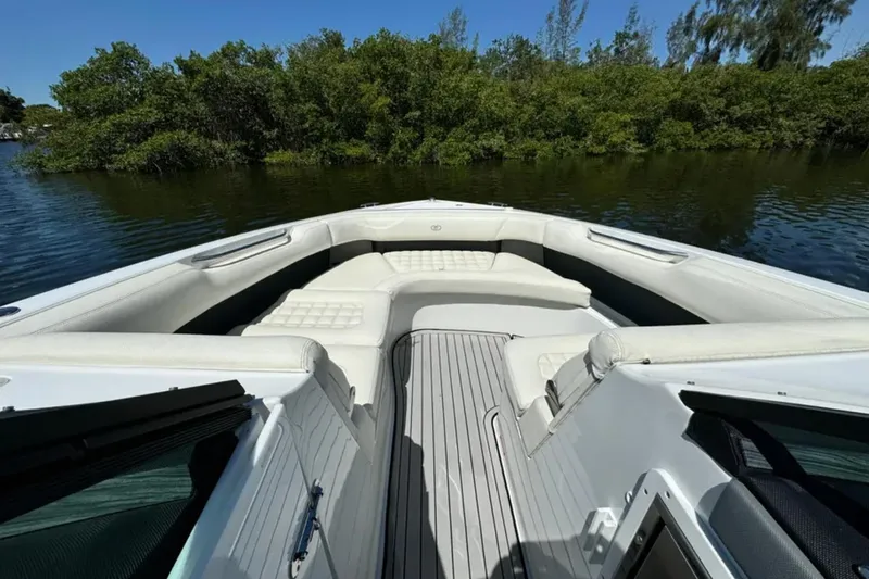  Yacht Photos Pics 2020 Cobalt R30 boat interior with white seating, on calm water near lush greenery.