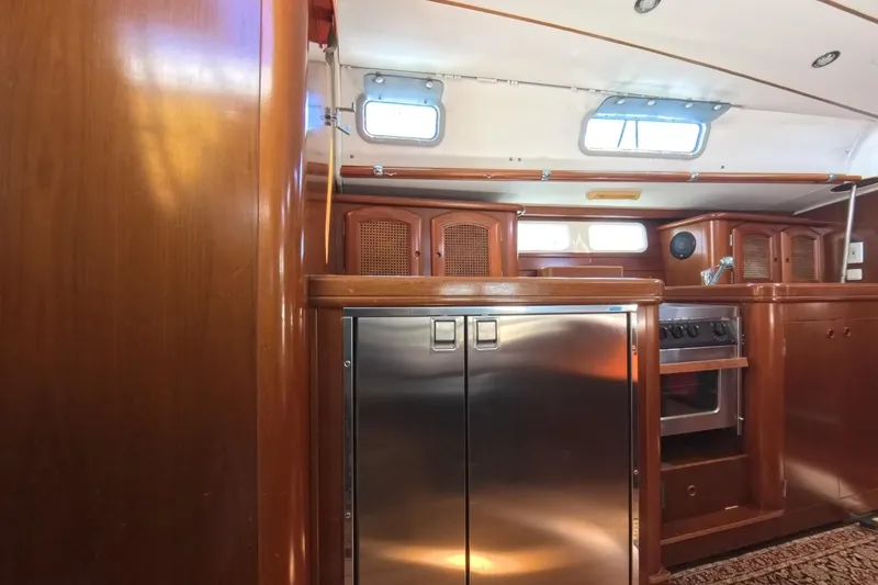 Prime Directive Yacht Photos Pics Interior of 1999 Beneteau Oceanis 461 yacht, featuring a modern kitchen with wood cabinetry.