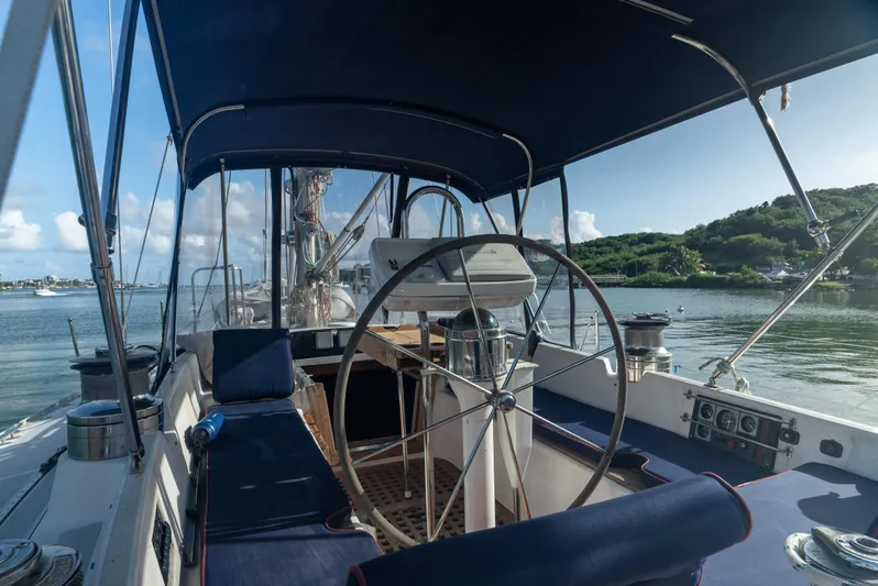 4 Knots Yacht Photos Pics Interior view of 1990 Hylas 51 sailboat cockpit with steering wheel and blue seating.