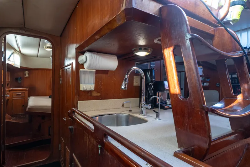 4 Knots Yacht Photos Pics Interior of 1990 Hylas 51 yacht, featuring wooden cabinetry and compact kitchen area.