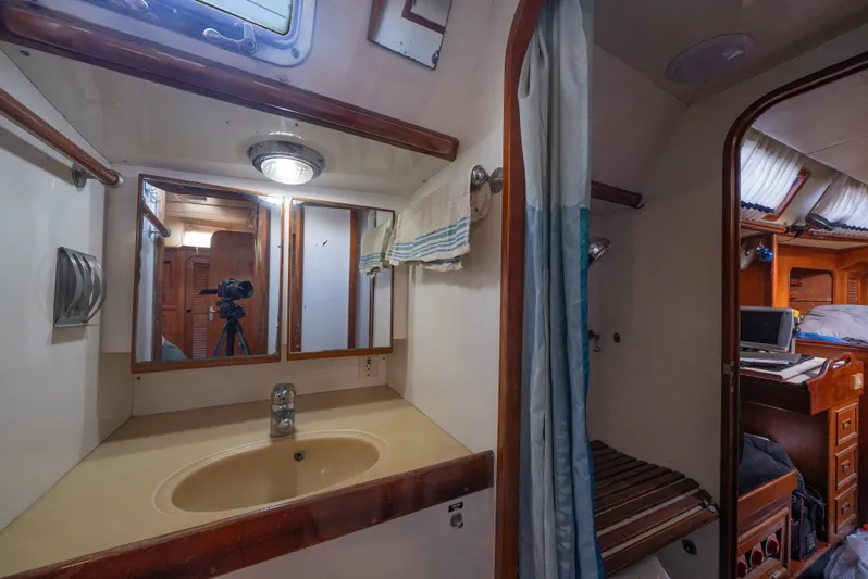 4 Knots Yacht Photos Pics 1990 Hylas 51 yacht bathroom with sink, mirror, and wooden accents.