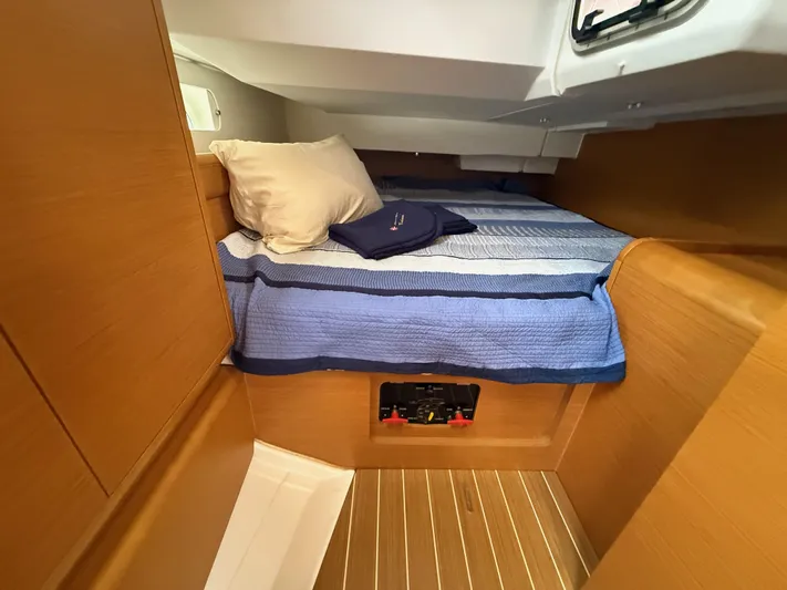 Kahuna Yacht Photos Pics Cozy cabin interior of 2011 Jeanneau 409 sailboat with striped bedding and wooden finish.