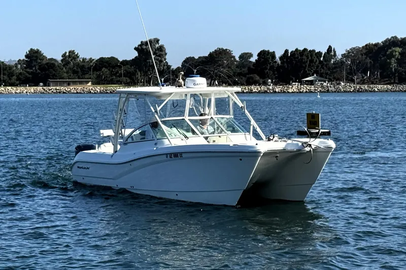  Yacht Photos Pics 2017 World Cat 295 DC boat cruising on calm waters near a wooded shoreline.