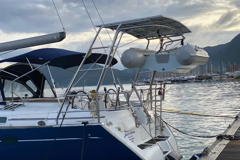 Milos Dream Yacht Photos Pics Beneteau Oceanis 50 sailboat, 2003 model, docked with inflatable dinghy, scenic marina backdrop.