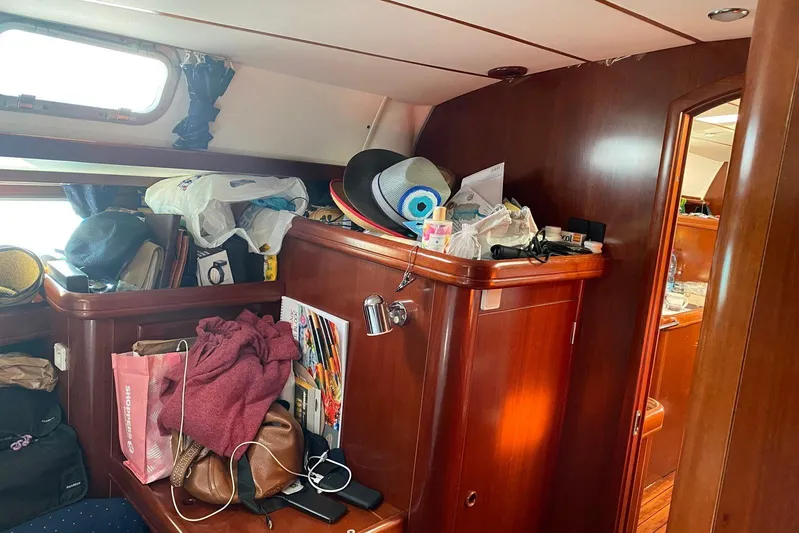 Milos Dream Yacht Photos Pics Cluttered cabin interior of a 2003 Beneteau Oceanis 50 sailboat with wooden furnishings.
