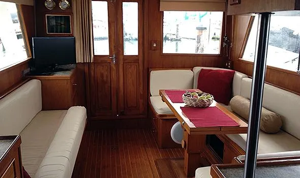Hullabaloo Yacht Photos Pics Interior of 1986 Sea Ranger 47 Pilothouse with cozy seating and wooden finishes.
