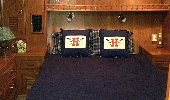 Hullabaloo Yacht Photos Pics Cozy bedroom in 1986 Sea Ranger 47 Pilothouse with nautical-themed pillows and wooden cabinetry.