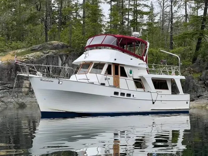 Hullabaloo Yacht Photos Pics 1986 Sea Ranger 47 Pilothouse yacht anchored near rocky shoreline with trees.