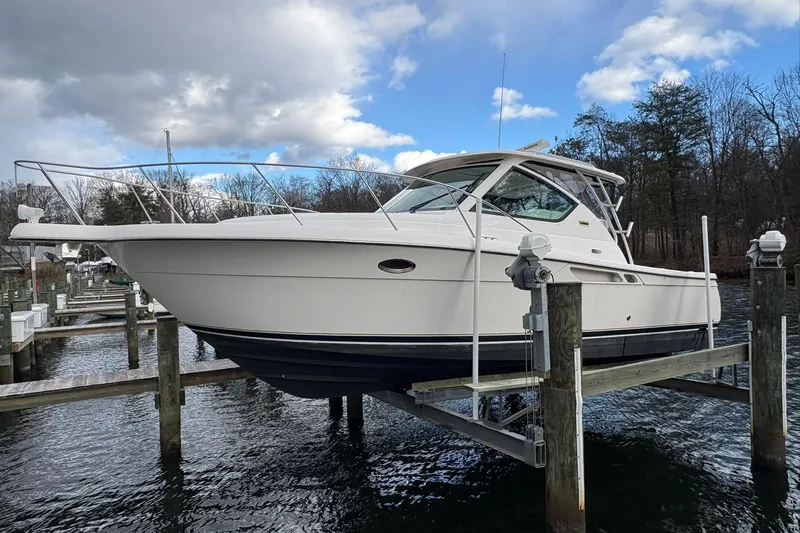  Yacht Photos Pics 2008 Tiara Yachts 3000 Open on lift, docked by wooded shoreline under cloudy sky.