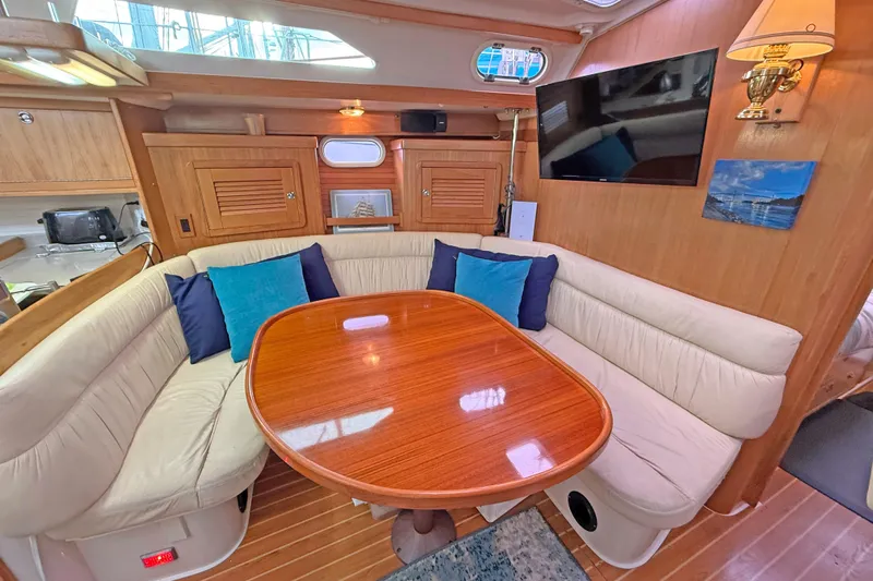 Shumka Yacht Photos Pics Luxurious interior of a 2005 Catalina 42 MkII sailboat with cozy seating and wooden table.