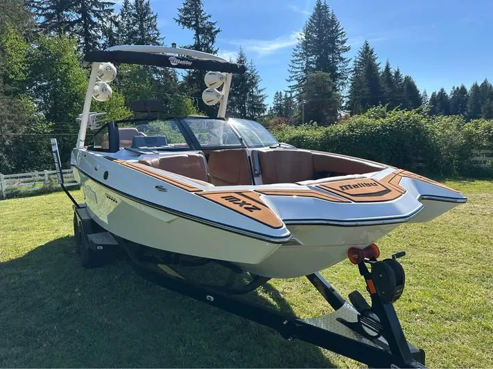  Yacht Photos Pics 2023 Malibu Wakesetter 23 MXZ boat on trailer, parked on grass with trees in background.