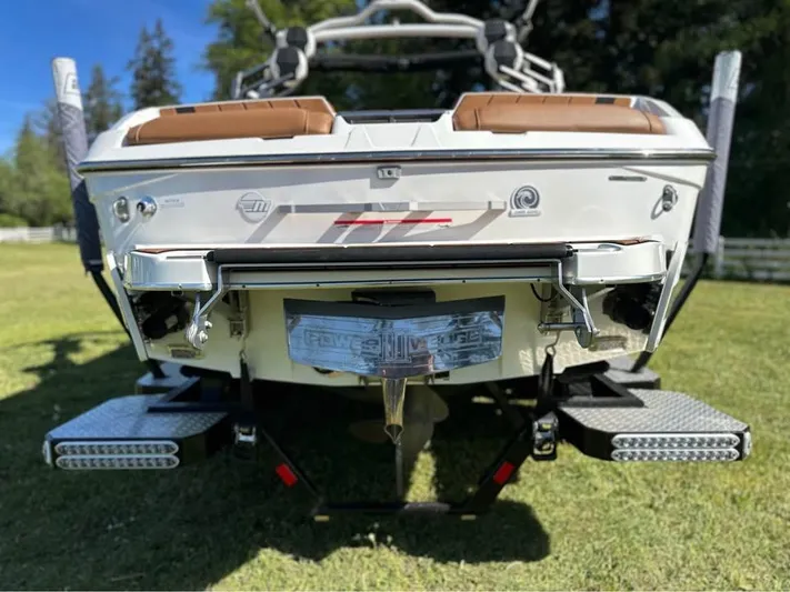  Yacht Photos Pics 2023 Malibu Wakesetter 23 MXZ boat rear view on grass, showcasing swim platform and propeller.