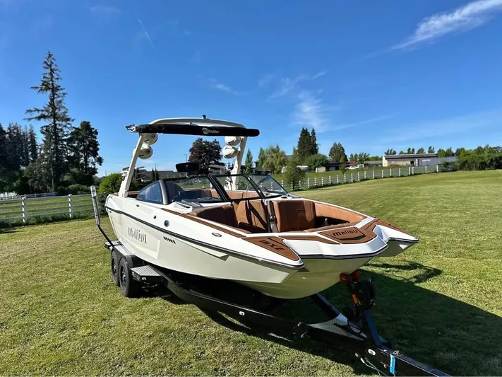  Yacht Photos Pics 2023 Malibu Wakesetter 23 MXZ boat on trailer in grassy field.