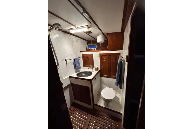 Savasa Yacht Photos Pics 1979 Cheoy Lee 46 LRC yacht bathroom with sink, toilet, and wooden cabinetry.