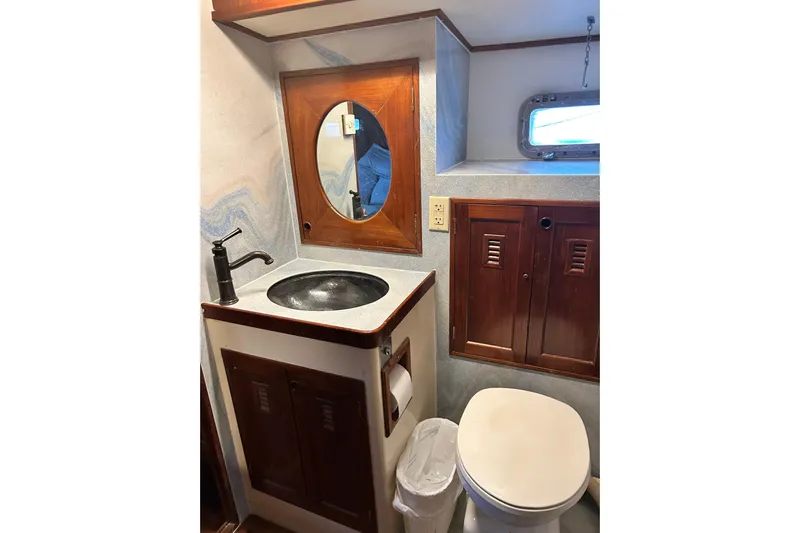 Savasa Yacht Photos Pics 1979 Cheoy Lee 46 LRC yacht bathroom with wooden cabinets and round mirror.