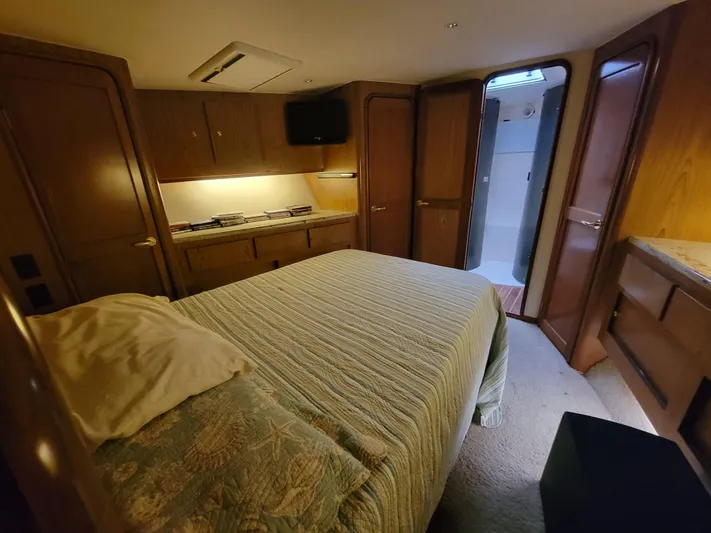  Yacht Photos Pics 1986 Ocean Yachts 55 Super Sport bedroom with ensuite bathroom, wood cabinetry, and TV.